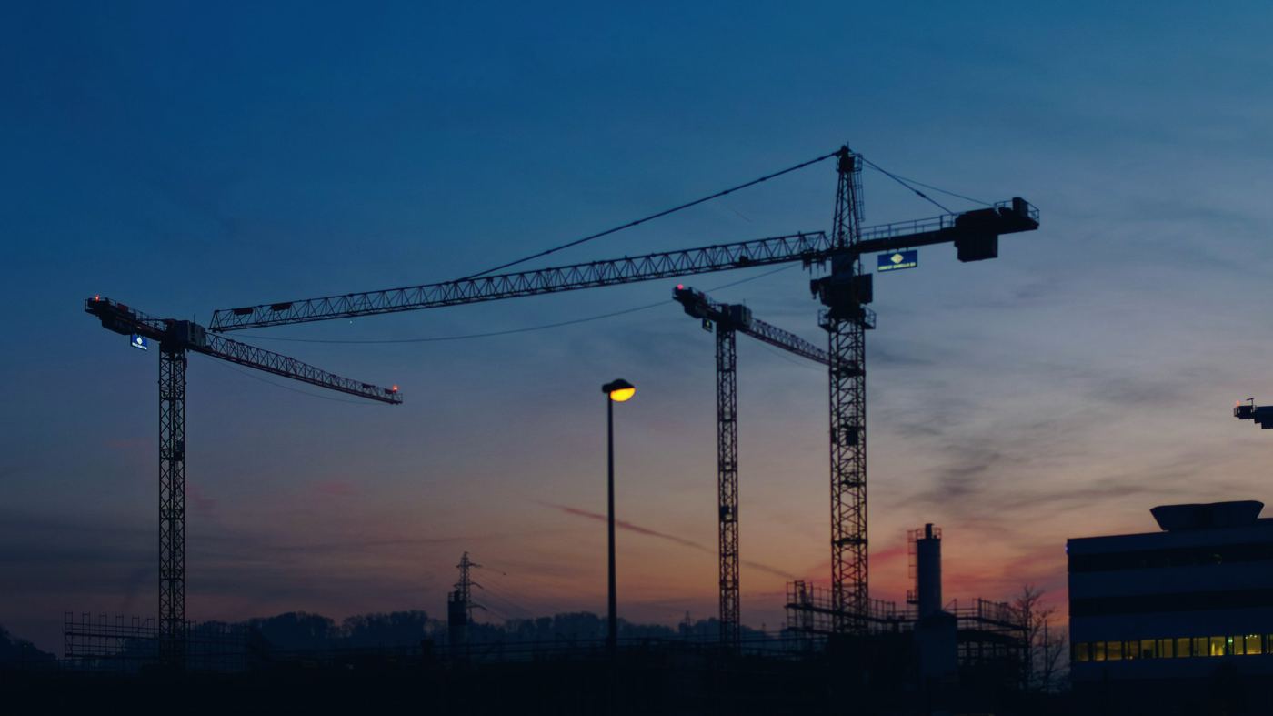 Tower cranes over a construction site at dusk