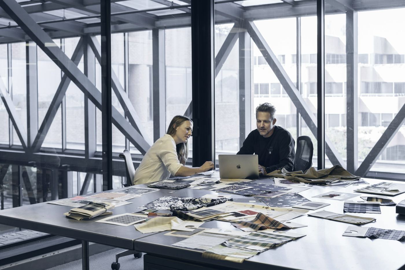 Two consultants reviewing documents at a large table in a glass office